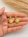Two gold feather stud earrings with blush marquise crystals resting on an open palm
