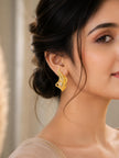 Woman wearing a gold feather stud earring with marquise crystal, hair in an updo