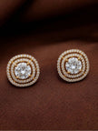 Pair of gold-plated double halo CZ stud earrings laid flat on dark brown fabric