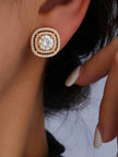 Gold-plated double halo CZ stud earring worn on a woman's ear against dark hair