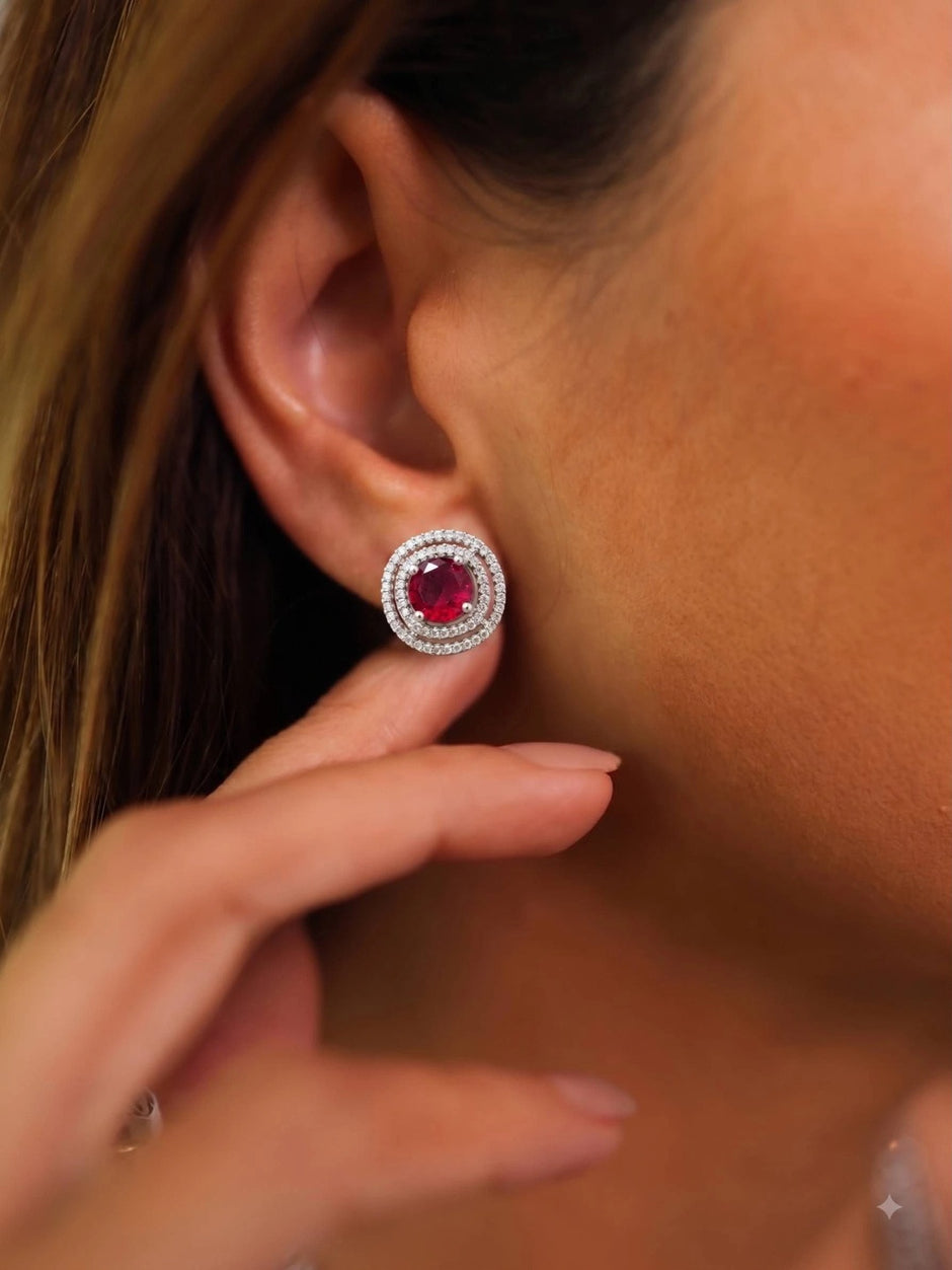 Model wearing a silver double halo ruby red stud earring on her right ear, side profile view