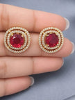 Two gold-plated ruby CZ double halo stud earrings resting on an open palm for size reference