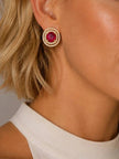 Woman wearing gold-plated ruby CZ double halo stud earring styled with a white sleeveless top
