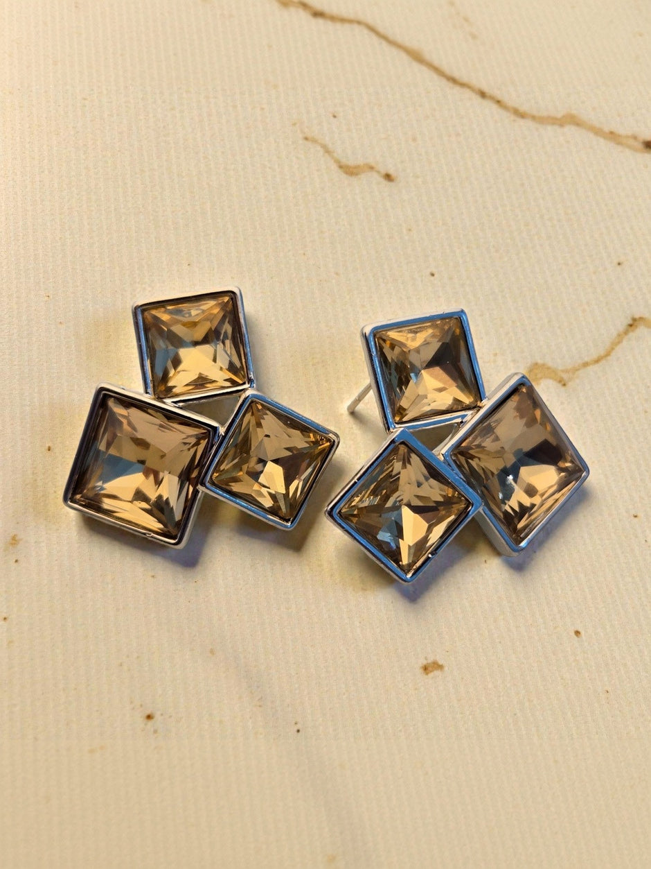 Both crystal square cluster stud earrings laid flat on a textured cream surface showing full design