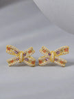 Pair of gold-plated bow stud earrings with multicolour zirconia, front view on grey surface