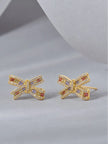 Two gold bow stud earrings with orange, lavender and yellow stones, angled flat-lay view
