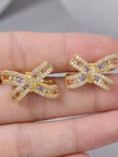 Close-up of multicolour CZ bow stud earrings held in a hand showing stone detail and size