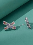 Close-up of two multicolour CZ bow stud earrings held between fingers showing stone detail