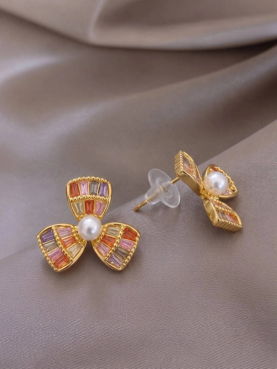 Side and front view of gold-plated flower studs showing push-back butterfly closure and petal detail on grey satin