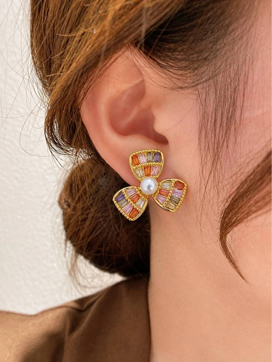 Gold-plated multicolour zirconia flower stud worn on a woman's ear showing scale and fit against skin