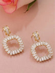Close-up pair of gold-plated circular baguette CZ drop earrings on pink fabric