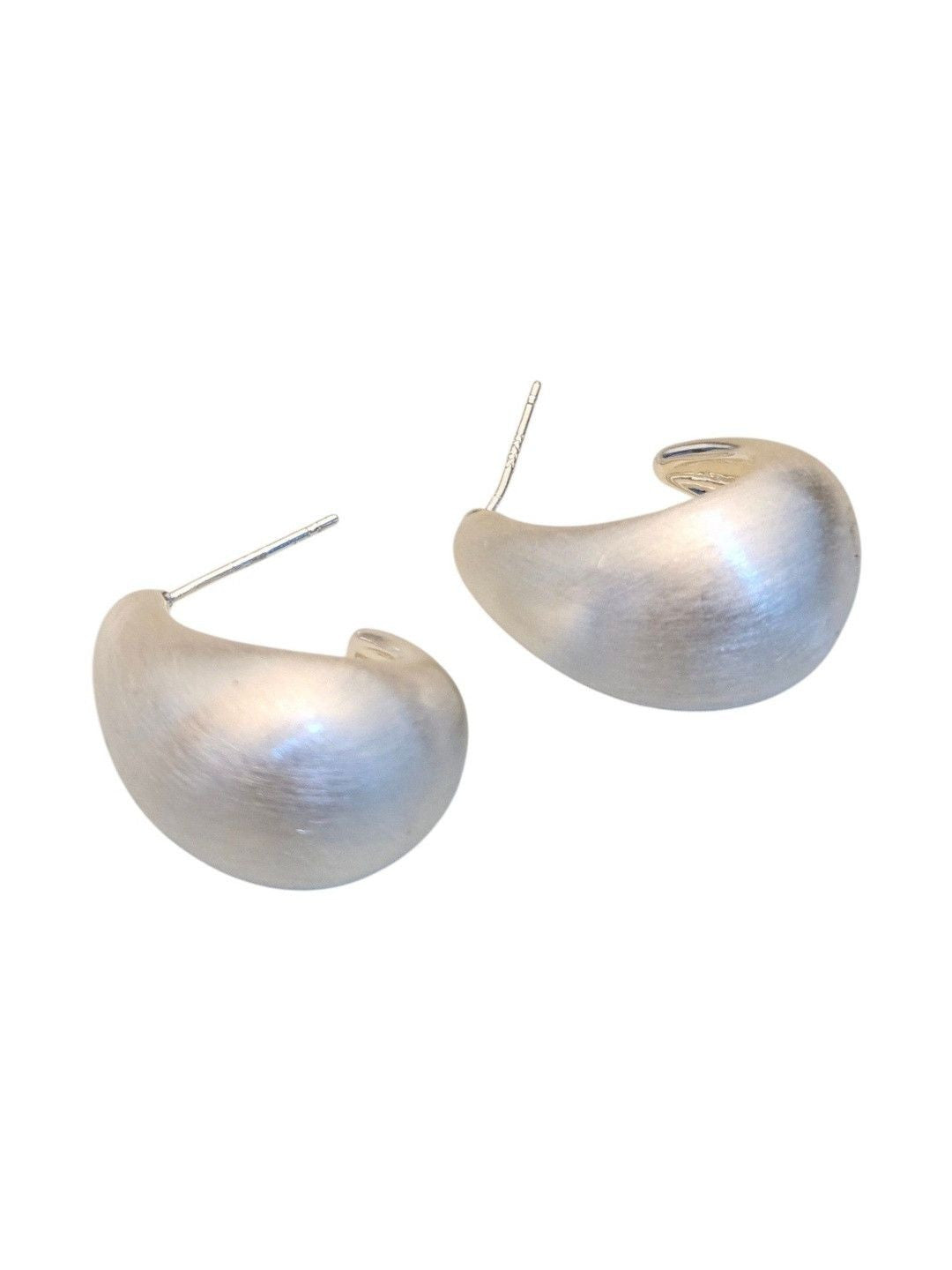 Close-up of two brushed silver chunky teardrop earrings with visible stud posts