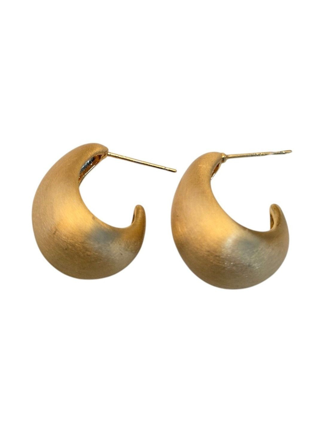 Pair of matte gold chunky hoop earrings shown on a beige surface highlighting the curved sculptural silhouette