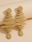 Two matte gold graduated oval disc earrings lying flat on a cream paper background showing full length