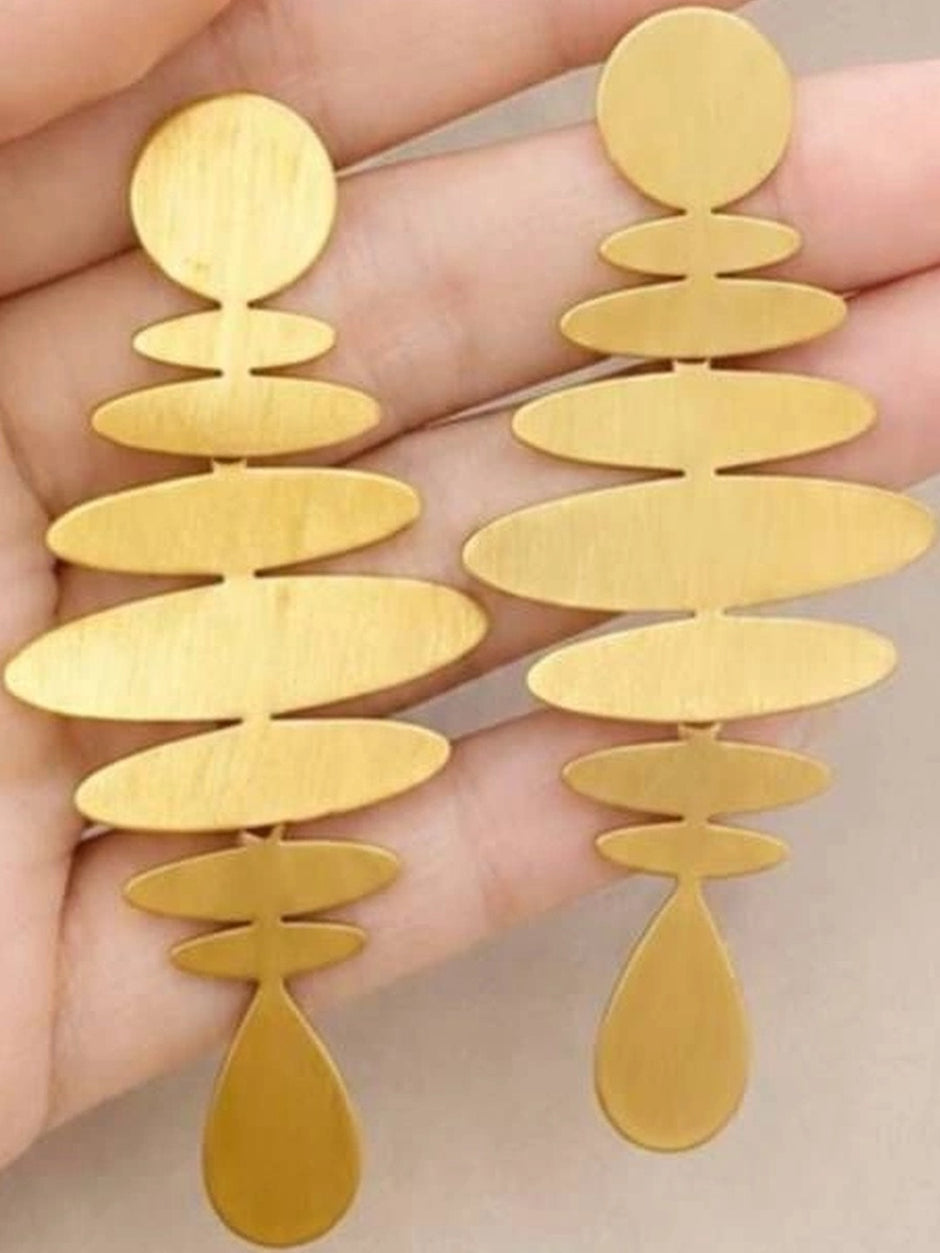 Close-up of both matte gold stacked oval drop earrings held in a hand showing brushed finish detail