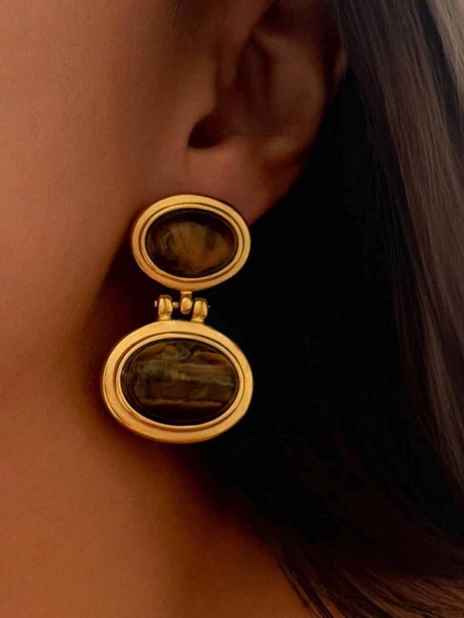 Model wearing gold-plated tiger eye double oval drop earring on the ear in close-up