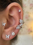Model wearing silver CZ butterfly studs, solitaire stud and double floral ear cuff styled across one ear
