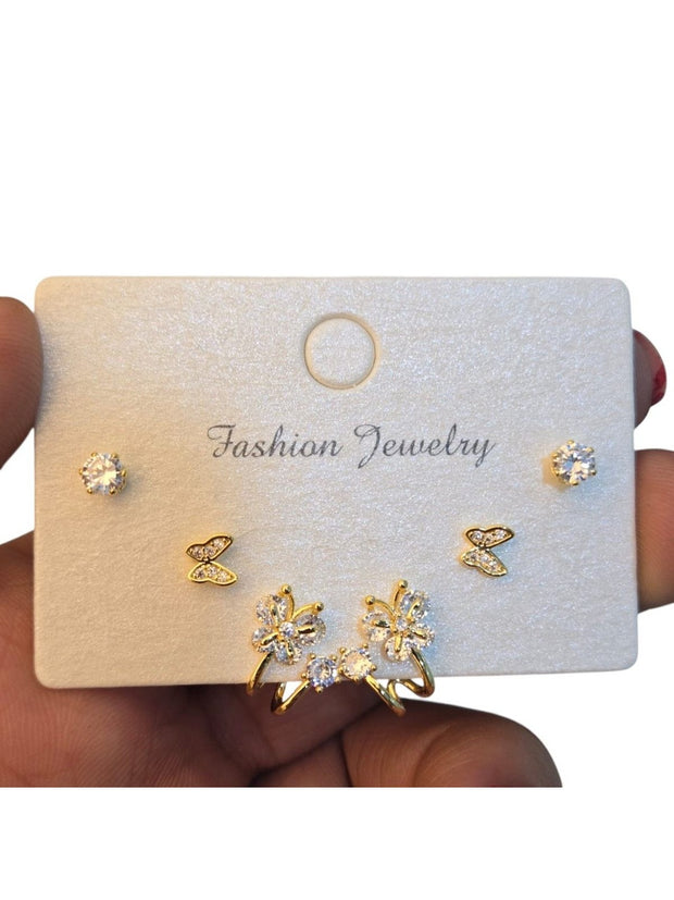 Three pairs of gold-plated CZ earrings on a white fashion jewellery card held in hand