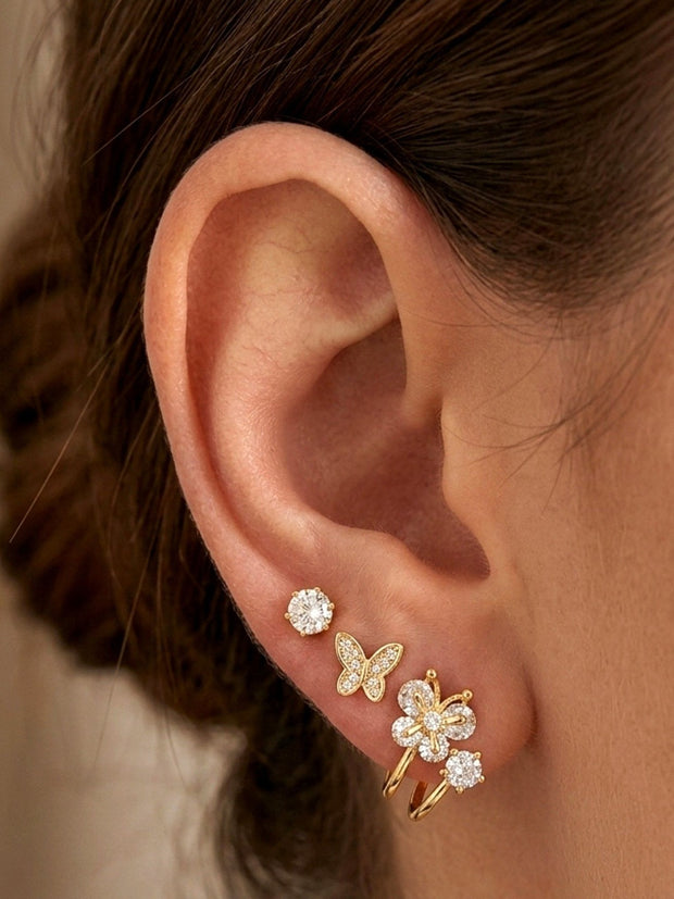 Gold CZ solitaire stud, butterfly stud, and floral ear cuff styled together on a model's ear