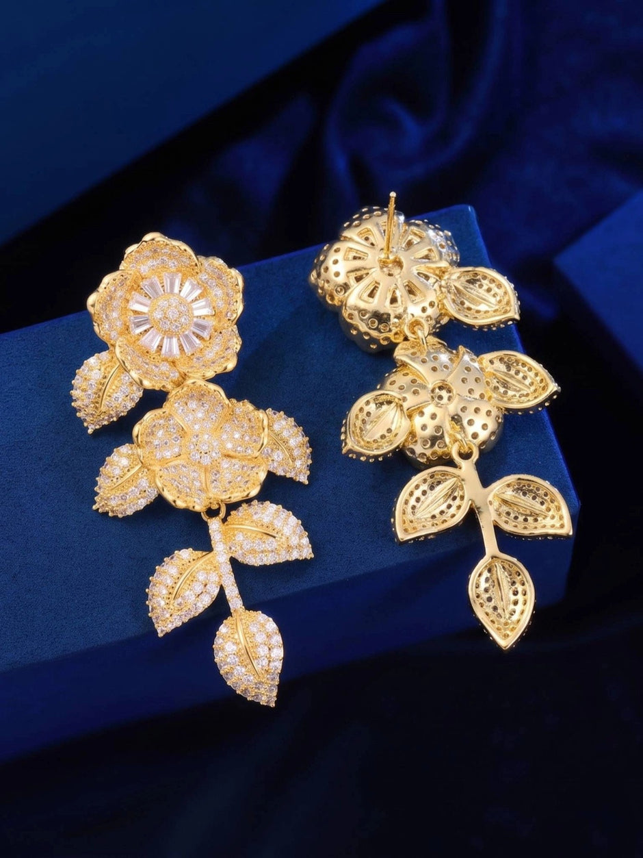 Front and back view of gold-plated floral earrings showing push-back post fitting on blue velvet