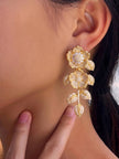 Gold-plated floral CZ drop earring worn on a model showing full length and scale against the ear