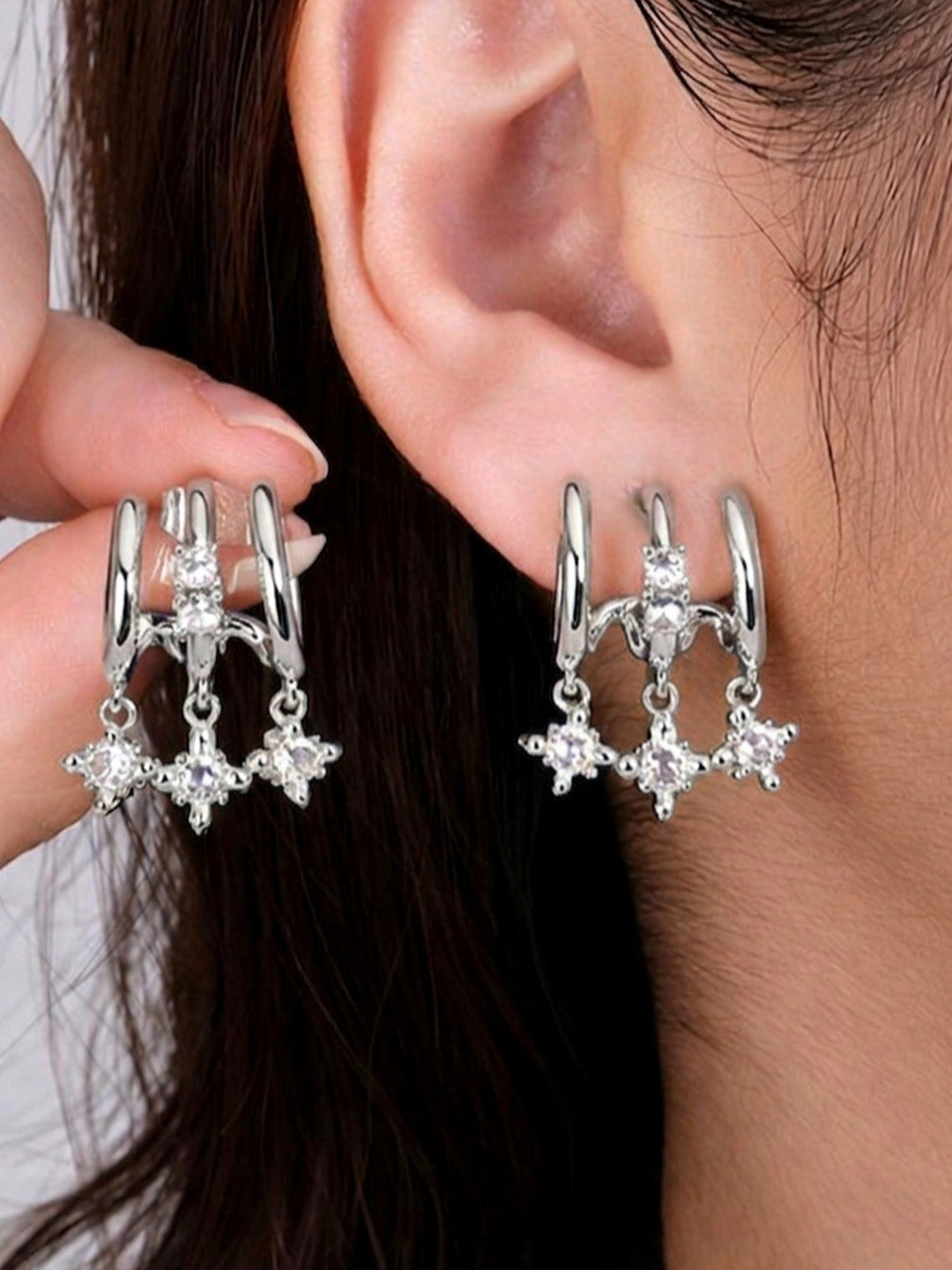 Silver CZ star charm double hoop earrings worn on a model's ear, showing front and back view