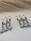 Close-up of both silver CZ star charm double hoop earrings placed on a marble surface