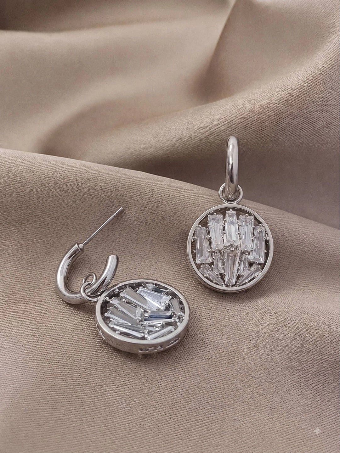 Side and front view of silver hoop and crystal disc earrings showing pin fastening detail