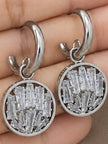 Close-up of silver circular drop earrings held in palm showing baguette crystal cluster detail