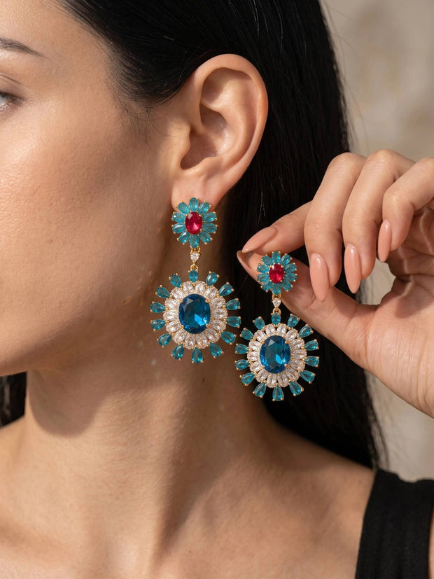 Woman wearing gold-plated teal and blue crystal floral drop earrings, shown from the side