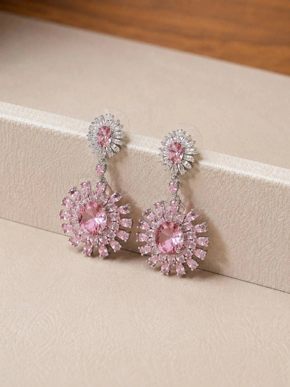 Close-up of pink floral drop earrings propped against a cream jewellery box edge showing push-back backs