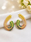 Pair of gold-plated multicolour CZ leaf half-hoop earrings laid flat on white fabric beside cream flowers