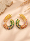 Pair of gold-plated multicolour CZ leaf half-hoop earrings displayed on a beige surface with dried grass stems