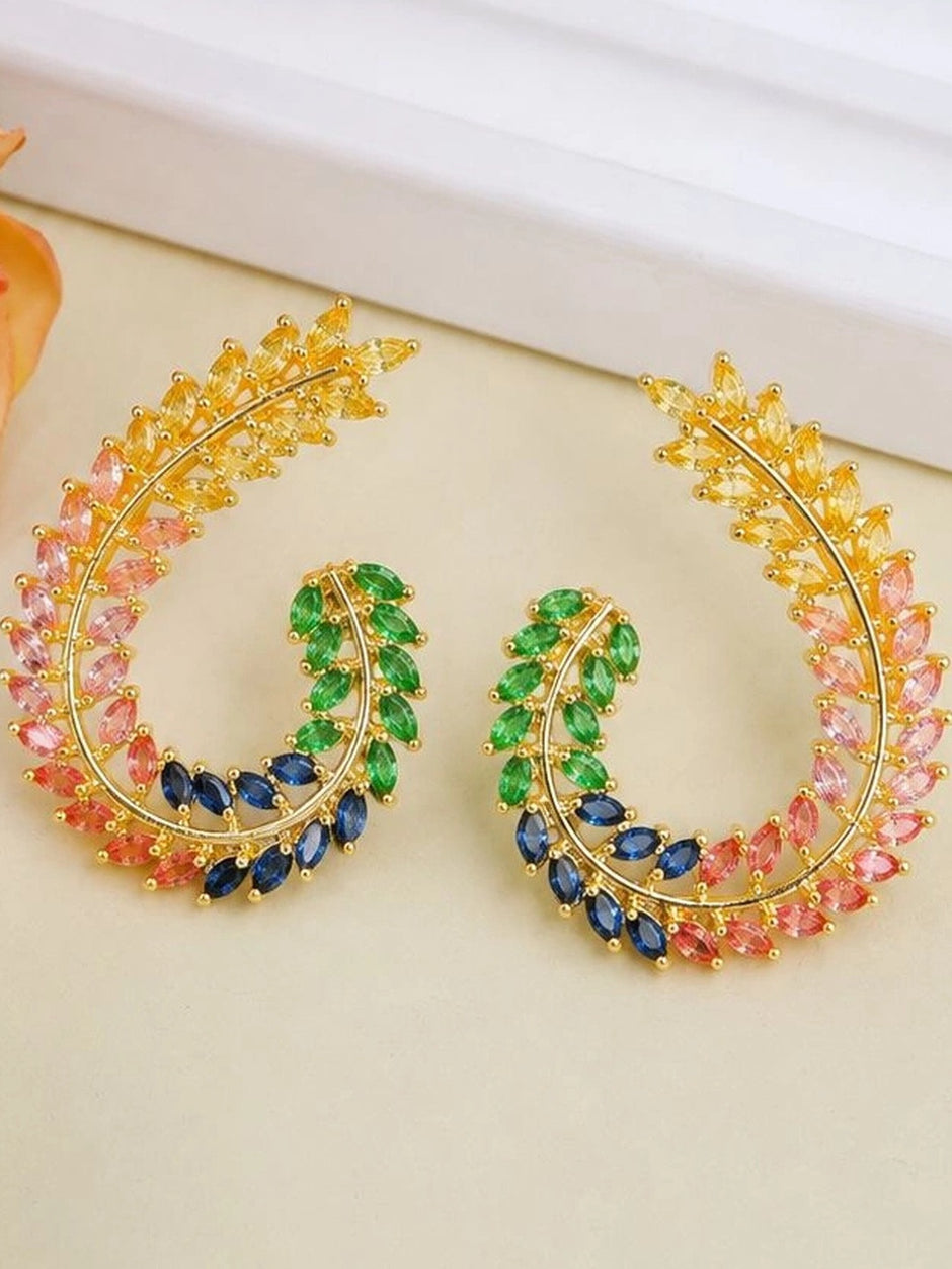 Close-up flat lay of both earrings on a cream surface showing yellow, pink, green, and navy marquise CZ stones