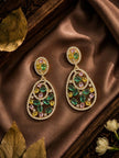 Pair of gold-plated multicolour CZ open teardrop earrings laid on brown satin fabric with flowers