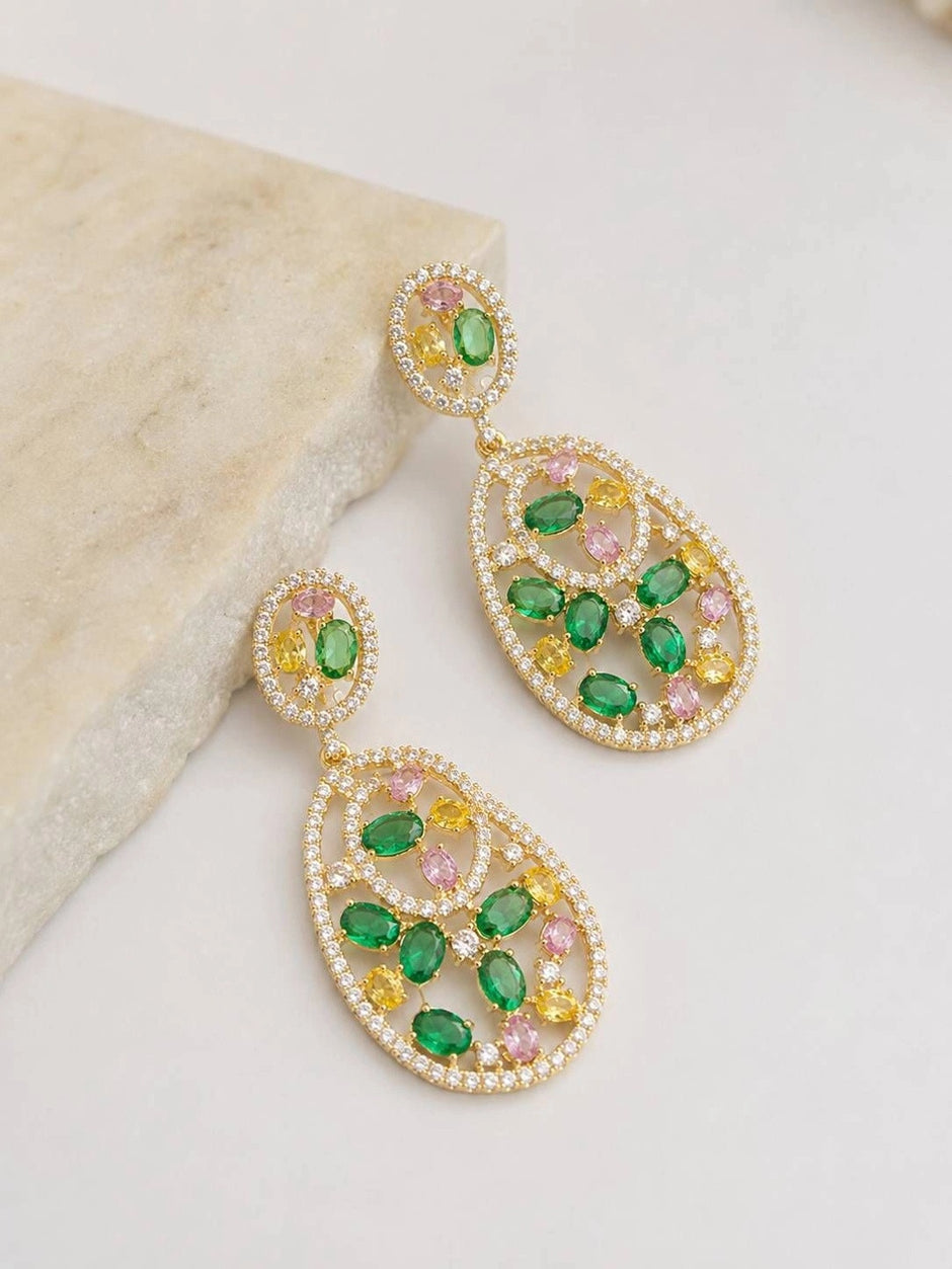 Two gold-plated multicolour CZ teardrop earrings displayed upright against a white marble surface