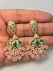 Close-up of both pink crystal and green zirconia gold-plated drop earrings resting on an open palm