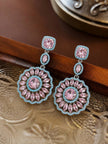 Pair of pink and blue zirconia circular drop earrings resting on a decorative silver tray