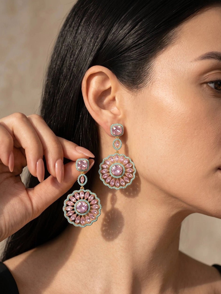 Woman wearing gold-plated circular drop earrings with pink crystals and turquoise bead border, side profile view
