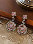 Pair of gold-plated pink crystal circular drop earrings resting on a decorative wooden and metal tray