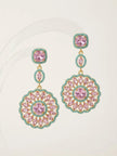 Gold-plated pink and turquoise circular drop earring pair displayed flat against a white curved acrylic surface