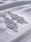 Pair of silver-tone pink and blue cubic zirconia chandelier earrings laid on grey satin fabric