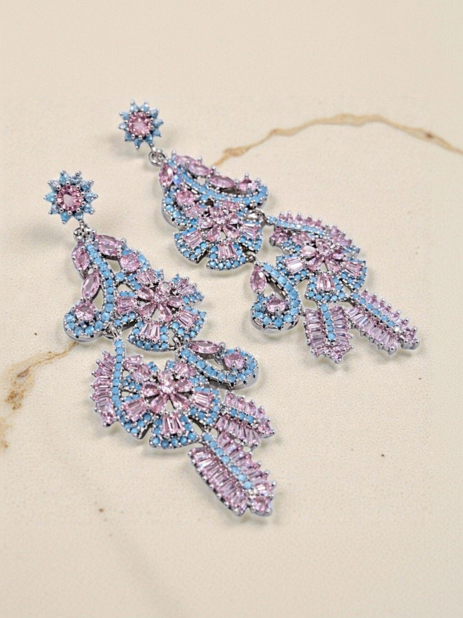 Pink and blue CZ chandelier earrings displayed on a cream marble surface showing full drop length