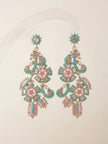 Pair of gold-plated floral chandelier earrings with pink baguette crystals and turquoise beads on clear stand