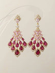 Pair of gold-plated ruby and blush-pink CZ chandelier earrings displayed upright on a white surface