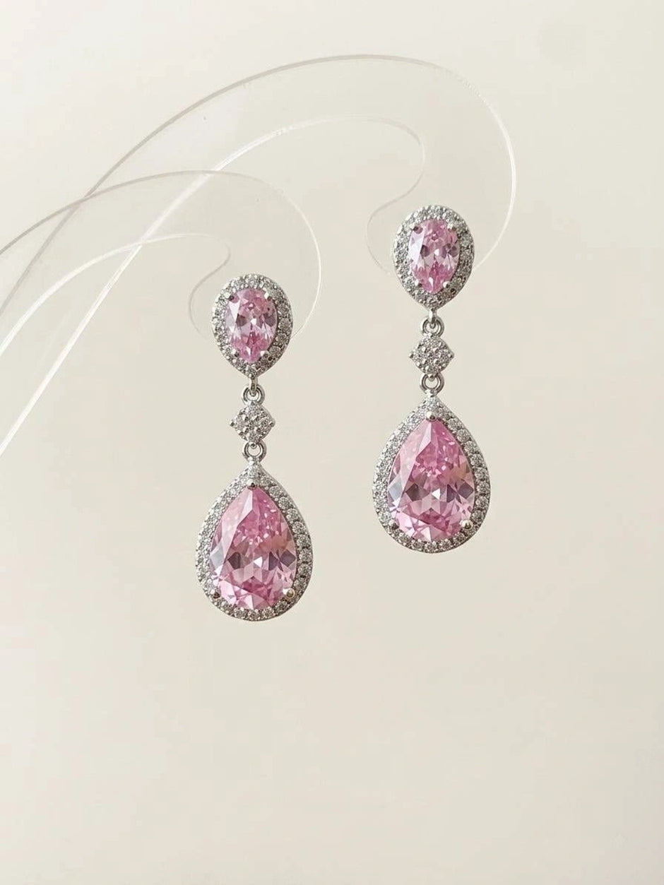 Close-up of pink CZ oval and pear teardrop earrings against a clean off-white background showing full design