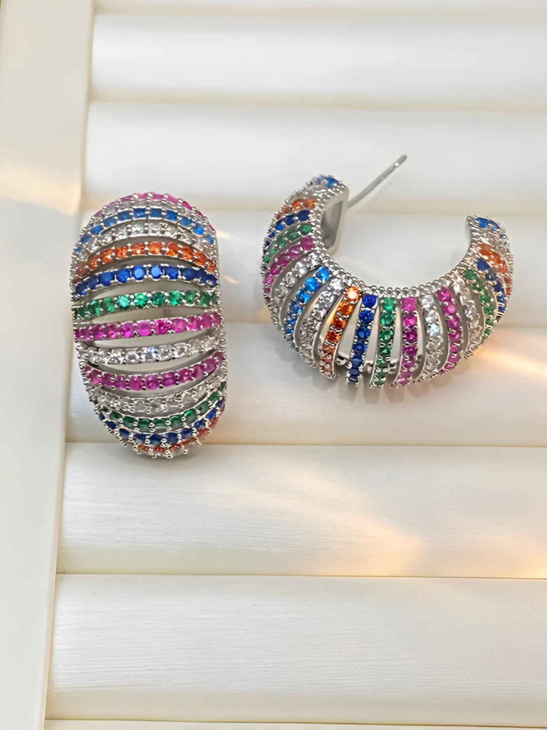 Front and side view of rainbow zirconia ribbed hoop earrings displayed on a white jewellery tray