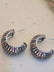 Two chunky multicolour zirconia hoops lying flat on palm displaying vibrant stone rows from above