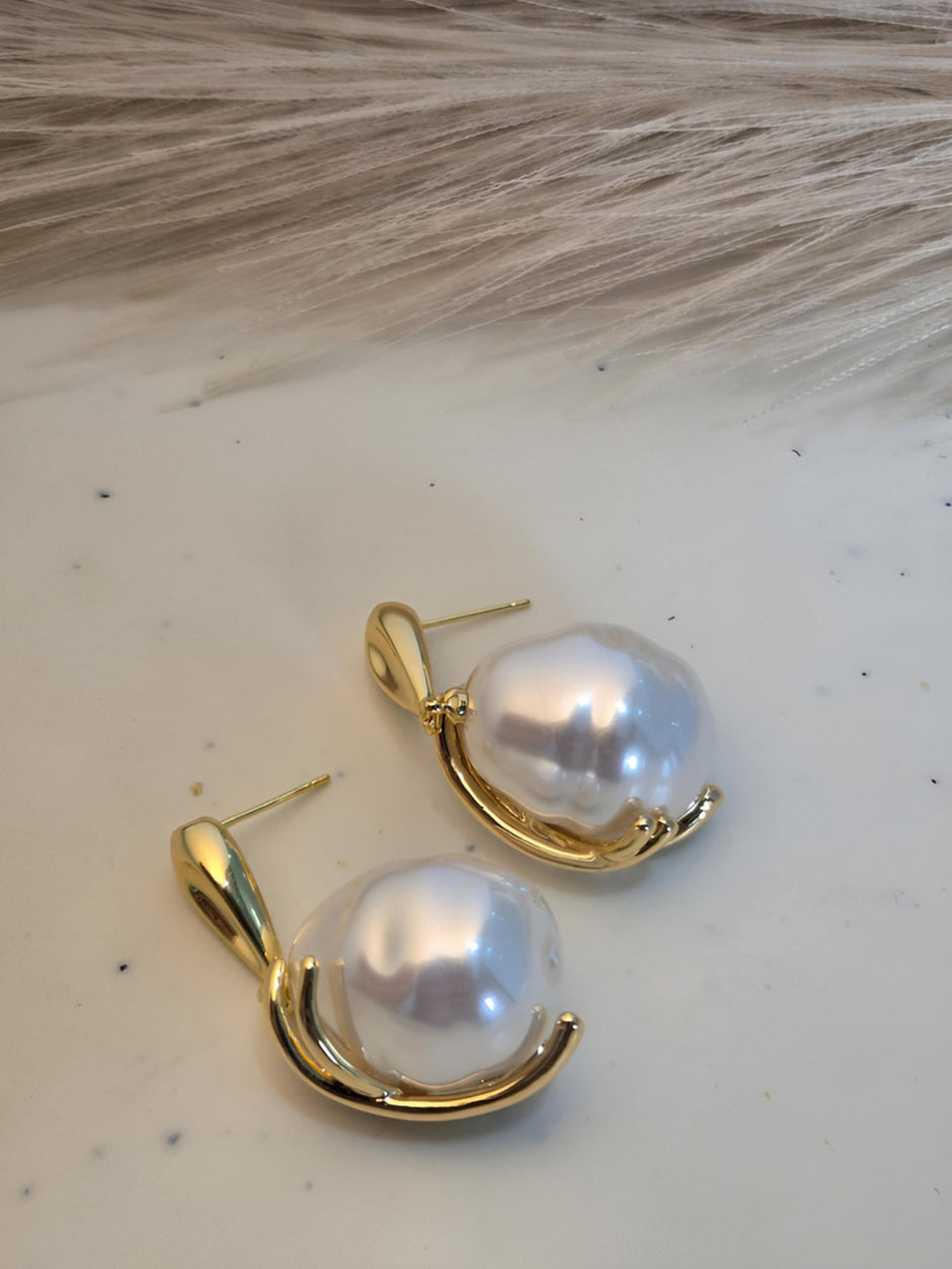 Back view of gold-plated baroque pearl drop earrings lying flat, showing push-back stud post and underside of pendant