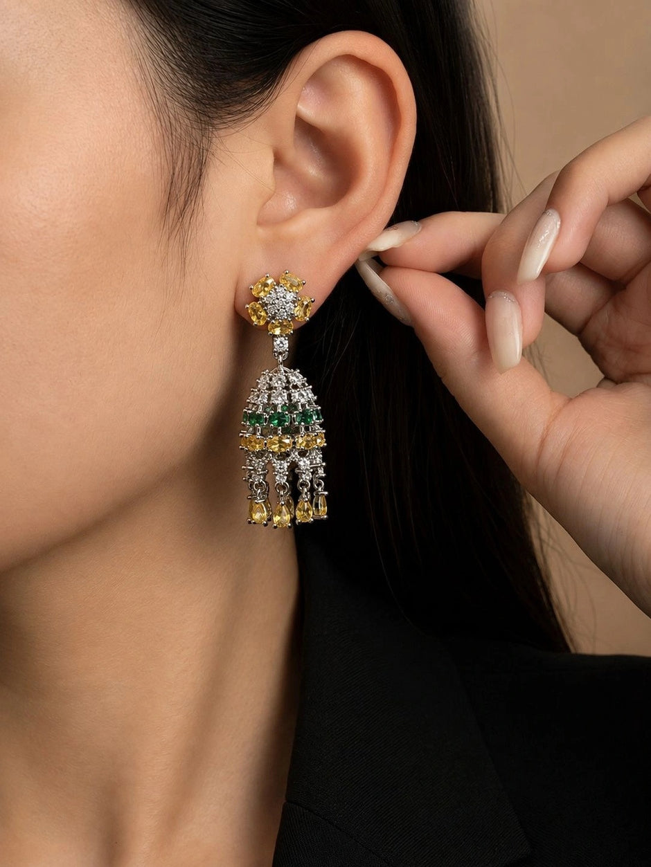 Model wearing silver-toned chandelier drop earring with yellow and green cubic zirconia tiers on left ear